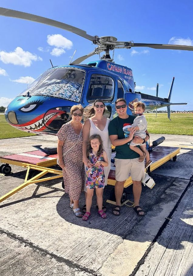A family with two young children in front of the helicopter